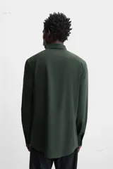 Camisa de vestir verde oscuro, corte slim fit, con cuello italiano, mangas largas con puños abotonados y cierre frontal con botones.