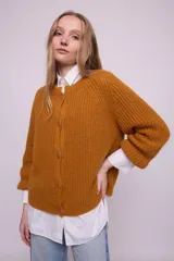 Cárdigan color ocre de tejido de punto con mohair, con cuello redondo, mangas largas y botones al tono. Silueta ligeramente oversize.