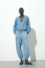 Pantalón jogger celeste confeccionado en lino, con tiro alto, cintura elástica ajustable con cordón, bolsillos delanteros y puños elásticos en el bajo.