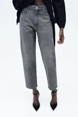 Pantalón de jean gris oscuro, de corte mom fit, tiro alto y largo tobillero. Cuenta con cinco bolsillos, cierre frontal con cremallera y botón.