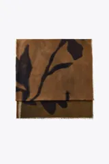 Pañuelo rectangular de modal con estampado de hojas en tonos marrón y negro, y terminaciones deshilachadas.