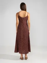 Vestido largo hasta el tobillo de viscosa y poliamida, con estampado de rayas verticales rosas y flores rojas. Tiene breteles finos, escote en V profundo y detalle de flor Polonio en cobre.