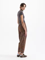 Pantalón de popelina con lycra color marrón, con estampado exclusivo de boquitas dinámicas en azul. Presenta pinzas en la cintura y el ruedo para un ajuste slim mom, cintura trasera elástica, bolsillos ojal en la espalda y bolsillos ocultos en los laterales. El acceso es mediante broche, cierre y botón interno a tono.