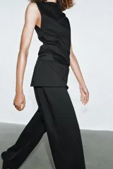 Top de algodón color beige, con cuello recto, mangas asimétricas y detalle de tejido drapeado en el lateral.