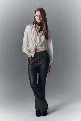 Pantalón jeanero de cuero ovino color marrón oscuro, de calce flare con efecto gastado y tachas aplicadas.