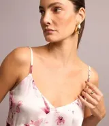 Blusa de viscosa satinada con estampado floral, breteles finos ajustables, escote en pico y volado diagonal.