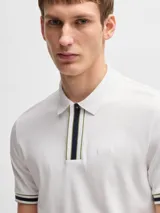 Polo de piqué de algodón color azul marino, corte regular fit, con cuello clásico, tapeta de dos botones con rayas en blanco y verde, mangas cortas con ribete a rayas y logo bordado en el pecho.