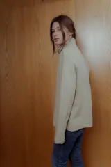 Chaqueta color beige de corte recto, cuello alto estructurado y cierre frontal con botones marrones.