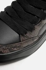 Zapatillas negras con estampado animal, de cordones y suela gruesa.