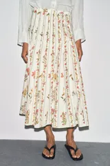 Falda midi de tiro medio confeccionada en hilatura de algodón. Tejido con tablas y estampado floral. Bajo acabado en vivo a contraste. Cierre lateral con cremallera oculta en costura.
