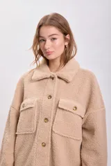 Sobrecamisa color beige de textura sherpa, con cuello clásico, cierre frontal con botones a tono, bolsillos de parche con solapa en el pecho y corte recto.