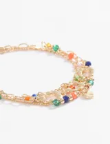Set de tres pulseras doradas con dijes de cuentas de colores y dijes circulares.