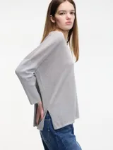 Sweater de hilo gris con textura brillosa, escote en V y manga larga.