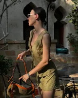 Conjunto de top y falda verde oliva con textura. El top es sin mangas, con escote en V y lazo ajustable en el centro. La falda es corta y ajustada.