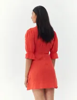 Vestido color coral con escote en V, mangas 3/4 abullonadas con puños elásticos y botones decorativos en el frente.