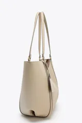 Bolso de hombro tipo shopper color beige, con doble asa y cierre imantado. Incluye una cartera interior con cierre de cremallera.