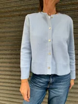 Cárdigan celeste tejido en lana con apliques de cuero y cintas tejidas.