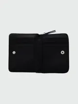 Billetera compacta con cierre de cremallera, color rosa pálido, con textura de cuero granulado y el texto "THE WALLET MARC JACOBS" estampado en el frente.