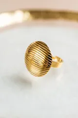 Anillo dorado con forma circular y diseño de líneas onduladas. Fabricado en acero quirúrgico con baño de oro de 18k.
