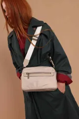 Bandolera color rosa viejo con detalles en cuero marrón claro, múltiples cremalleras metálicas y herrajes plateados. Incluye correa ancha ajustable con el logo de la marca.