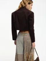 Blazer cropped marrón oscuro con solapa en la parte delantera y camisa desmontable mediante botones. Confeccionado en 97% algodón y 3% elastano.