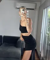 Vestido midi negro con corte asimétrico, una manga, abertura lateral y frunce en la cintura.