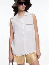 Camisa sin mangas confeccionada en lino color blanco, con cartera abotonada en la parte baja de la espalda, bolsillo delantero y bordado tipo pespunte en color contraste tanto en el frente como en el canesú de la espalda.