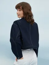 Campera corta de jean azul oscuro con costuras en hilo color crema, cuello mao y cierre con botones metálicos.