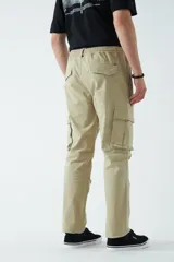 Pantalón cargo color beige, con cintura elástica ajustable con cordón, bolsillos laterales con cierre y bolsillos cargo con solapa.