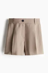 Short color beige de corte sastrero, con cierre y botón, bolsillos al bies y bolsillo trasero decorativo. Piernas con pinzas y pliegues adelante y atrás.