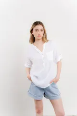 Camisa azul de lino con escote en V abotonado, bolsillo frontal y mangas 3/4 con trabilla.