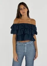 Top azul de algodón con escote off-shoulder y diseño de tres niveles de volados superpuestos.