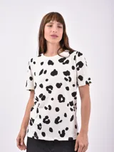 Remera blanca con estampado de manchas negras tipo animal print.