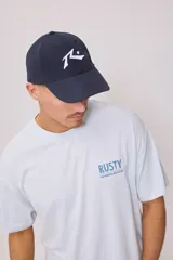 Gorra azul marino con logo de la marca Rusty bordado en blanco en el frente.
