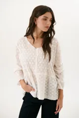 Camisa blanca con bordado floral, cuello en V y cierre frontal con botones.
