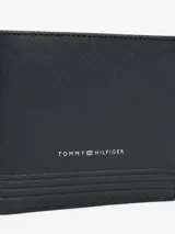 Billetera Tommy Hilfiger de cuero granulado color negro, con diseño plegable, múltiples ranuras interiores para tarjetas, bolsillo interior para monedas, logo en relieve en el pequeño bolsillo delantero y logo metalizado en la parte delantera.