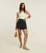 Short pollera de cintura alta color azul marino, confeccionado en tejido plano. Presenta solapas delanteras simulando bolsillos y un recorte en V en el ruedo.