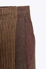Pantalón de tiro medio confeccionado en hilatura de lino 100%. Cintura con elástico en espalda ajustable con cordones. Bolsillos laterales ocultos en costura y de plastrón en espalda.