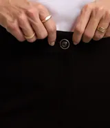 Pantalón legging negro de punto roma con botones dorados decorativos.