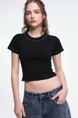 Remera blanca de algodón con cuello redondo y mangas cortas, con detalle de tachas plateadas en cuello y mangas.