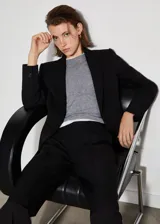 Blazer negro entallado con solapas de muesca, hombros estructurados, abertura posterior y dos bolsillos de ribete delanteros.