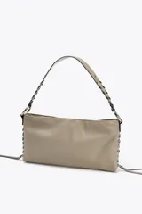 Bolso de hombro marrón de cuero sintético con dos bolsillos frontales con cremallera y tiras decorativas. El asa es trenzada y tiene herrajes metálicos.
