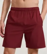 Bermuda deportiva color beige, de tejido plano de poliéster, con cintura elástica y cordón de ajuste. Posee bolsillos laterales con cierre y recortes laterales con perforaciones.