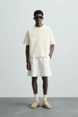 Bermuda color arena de tejido interlock de algodón con elasticidad, corte relaxed fit, cintura elástica ajustable con cordón interior, bolsillos laterales y bolsillo trasero de plastrón.