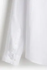 Camisa blanca de lino con cuello inglés, tapeta clásica y canesú en la espalda. Mangas largas con tapeta de manga y botón, y cierre ajustable de botón en los puños. Bajo redondeado. Corte estándar.