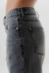 Pantalón jean de tiro medio color negro, corte mom, con bolsillos delanteros y traseros. Largo hasta el tobillo. Confeccionado en algodón 100%.