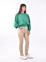 Pantalón de vestir color beige, de corte recto, con bolsillos laterales y traseros. Se ajusta a la cintura con cinturón de cuero marrón.