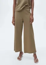 Pantalón palazzo color caqui, de tiro alto y corte crop. Con cintura elástica y confeccionado en tejido de algodón, poliamida y lino.
