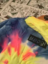 Canguro con capucha de algodón, estilo tie-dye en tonos amarillo, rosa, azul y violeta. Estampa frontal de una calavera con la frase "Where is my mind?". Cordones de ajuste azules.