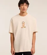 Remera color crema de corte relajado, cuello redondo y manga corta. Estampado frontal con el personaje de Garfield.